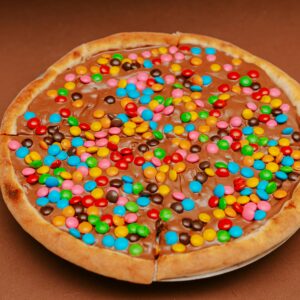 A delicious chocolate pizza topped with colorful candy coated chocolates, perfect for a sweet treat.