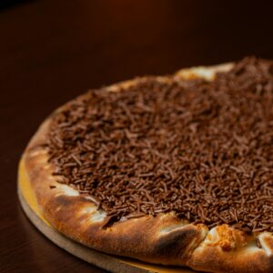 Mouthwatering chocolate-covered pizza on a wooden table, perfect for dessert lovers.